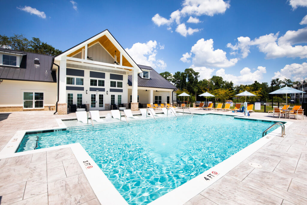 pool with view of clubhouse, in-pool loungers, and seating