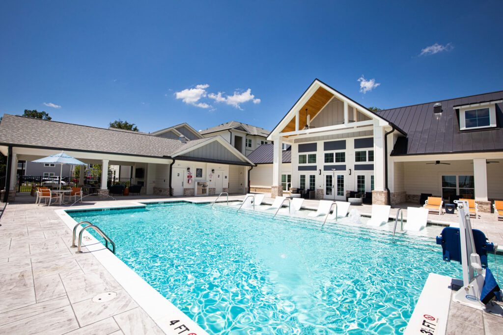 pool with view of clubhouse, in-pool loungers, seating, and covered lounge