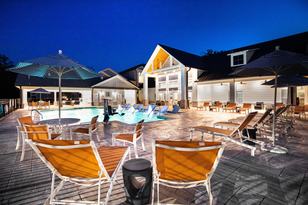 night view of the clubhouse and pool with loungers