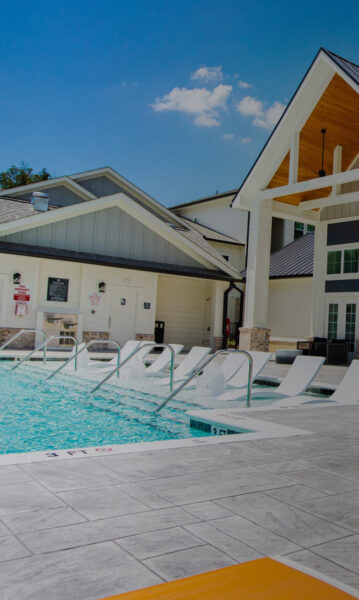 pool view with in-water chairs and partial view of clubhouse